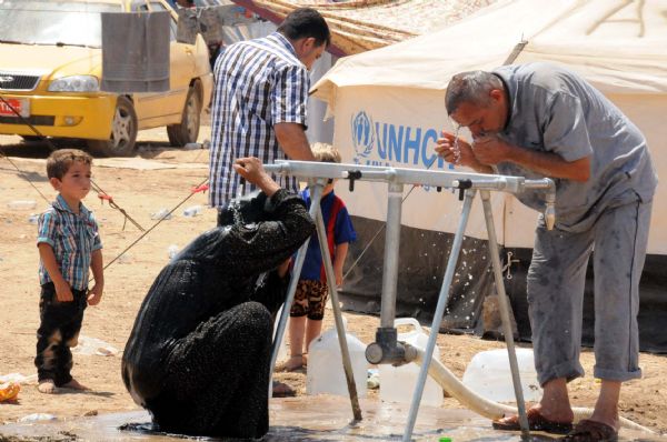 Mülteci kadınlar elbiseleriyle banyo yapıyor